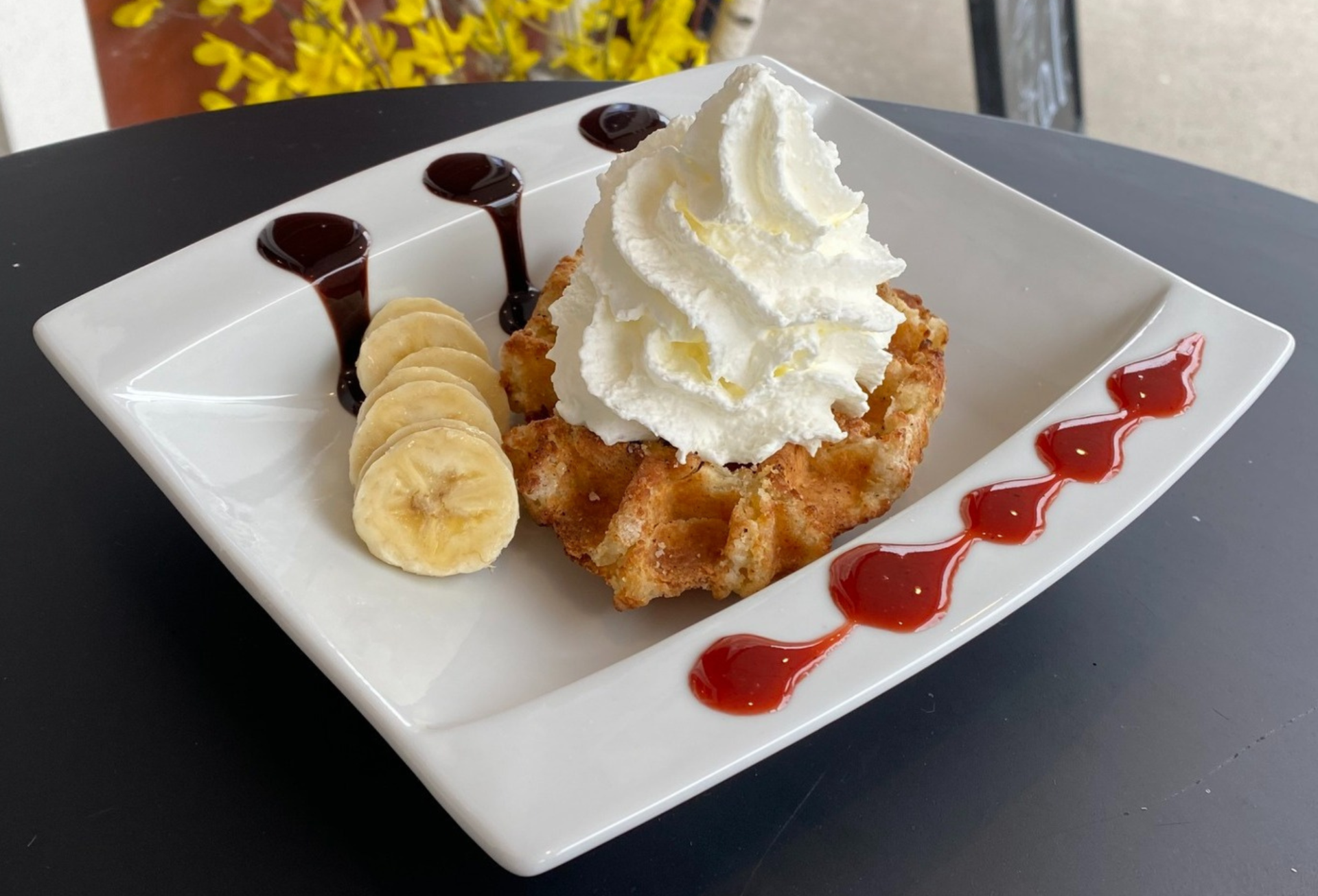 Fresh pastry with whipped cream and chocolate drizzle at Euphie d’ici café in Embrun.